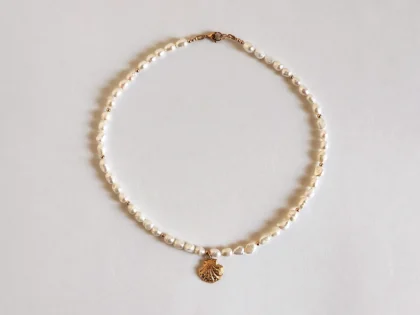 Collana di perle con ciondolo marino. Collana con ciondolo centrale, a forma di conchiglia dorata.